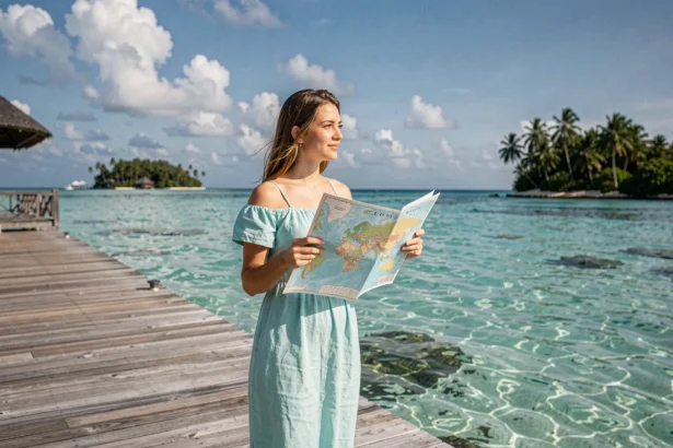 Voyageuse consultant une carte du monde aux Maldives sur un ponton en bois au-dessus du lagon turquoise